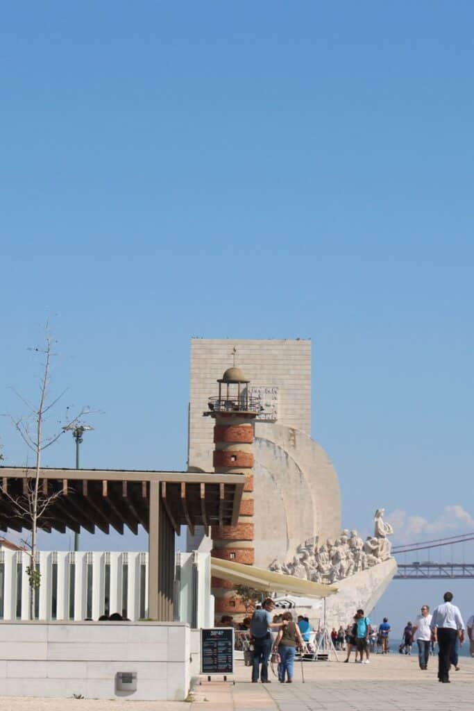 Distant view of the Discoveries Monument with a red lighthouse in the forefront