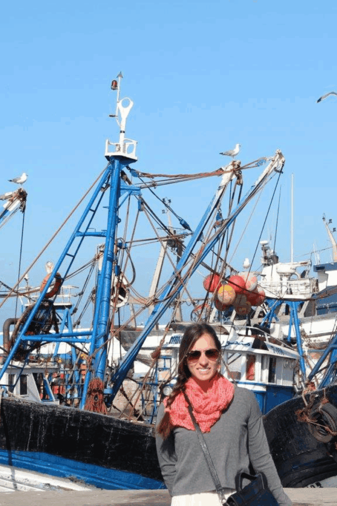 A woman standing in front of a fishing boat in Essouira Morocco